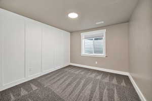 Empty room with dark carpet and baseboards