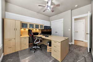 Office with a ceiling fan and dark carpet
