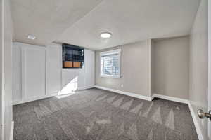 Empty room featuring carpet flooring and a textured ceiling