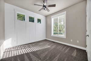 Unfurnished room with dark carpet and a ceiling fan