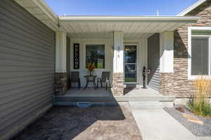 Entrance to property with stone siding and a porch