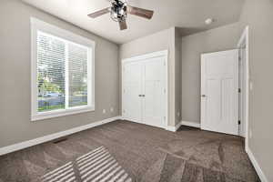 Unfurnished bedroom featuring dark carpet, a closet, and a ceiling fan