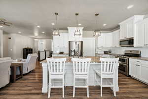 Kitchen with appliances with stainless steel finishes, an island with sink, white cabinetry, a kitchen bar, and recessed lighting