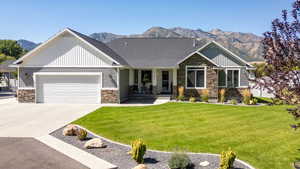 Craftsman-style house with stone siding, covered porch, and a front lawn