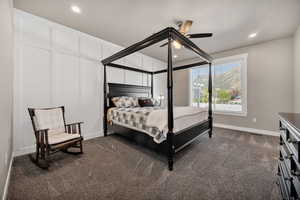 Bedroom with dark carpet, a ceiling fan, recessed lighting, and a decorative wall