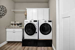 Washroom with cabinet space, dark wood-style floors, and separate washer and dryer