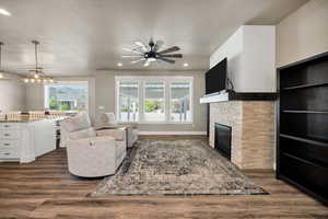Living area featuring a fireplace, dark wood-style flooring, plenty of natural light, recessed lighting, and a textured ceiling