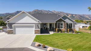 Craftsman-style house featuring stone siding, a porch, a mountain view, and driveway