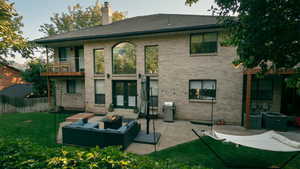 Back of house with a patio, a balcony, french doors, a chimney, and an outdoor living space with a fire pit