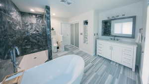 Primary Bathroom with a freestanding soaking bath, vanity, walk in shower, and recessed lighting