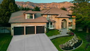 View of front of house featuring a mountain view, concrete driveway, a chimney, a tile roof, and brick siding