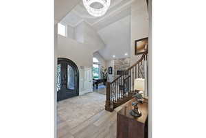 Entryway with stairs, light wood finished floors, crown molding, high vaulted ceiling, and a chandelier