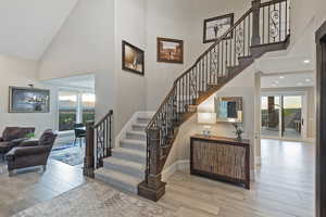 Stairs with high vaulted ceiling and wood finished floors