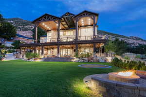 Back of property with a fire pit, a patio area, a lawn, and a mountain view