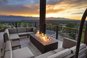 Balcony at dusk with an outdoor living space with a fire pit, a patio, and a mountain view