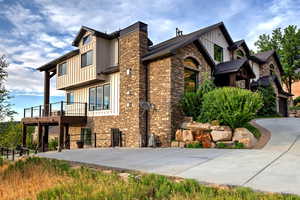View of property exterior with board and batten siding, a patio, and a wooden deck