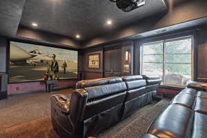 Carpeted cinema with a tray ceiling and recessed lighting