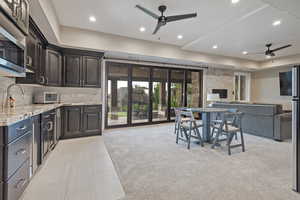 Kitchen with a ceiling fan, light stone counters, open floor plan, recessed lighting, and backsplash