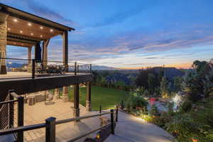 Patio terrace at dusk with a lawn, a mountain view, and a patio