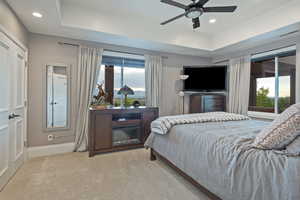 Bedroom with a tray ceiling, recessed lighting, light carpet, ceiling fan, and access to exterior