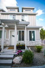 Doorway to property with stone siding, a porch, and board and batten siding