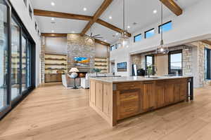 Kitchen with brown cabinetry, beamed ceiling, high vaulted ceiling, pendant lighting, and a large island
