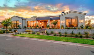 View of front of house with stone siding, stucco siding, and a front lawn