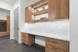 Kitchen featuring decorative backsplash, light stone counters, and brown cabinetry
