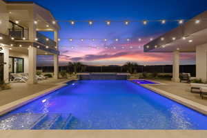 View of pool with a patio area, a balcony, a pool with connected hot tub, and a fenced backyard