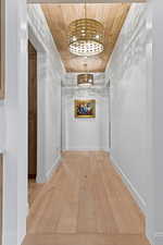 Corridor featuring hardwood / wood-style floors, wooden ceiling, and a chandelier