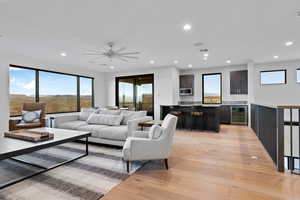 Living area with light wood-style floors, recessed lighting, wine cooler, and ceiling fan