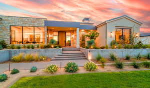 View of front of property with stone siding, stucco siding, and covered porch