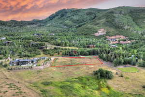 Aerial view at dusk of property boundaries highlighted, a mountain view, and a view of trees