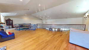 Unfurnished room featuring light wood finished floors, recessed lighting, lofted ceiling, and a chandelier