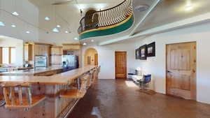 Kitchen featuring arched walkways, recessed lighting, stainless steel appliances, light brown cabinetry, and a breakfast bar