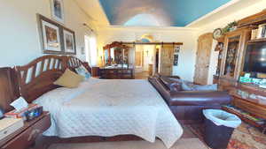 Carpeted bedroom featuring a barn door and lofted ceiling
