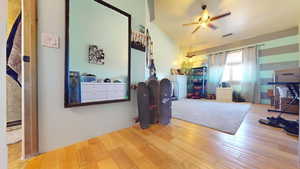 Bedroom with wood finished floors, ceiling fan, and vaulted ceiling