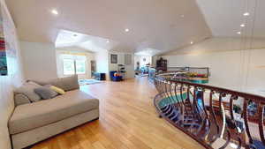 Sitting room with lofted ceiling, light wood finished floors, recessed lighting, and an upstairs landing