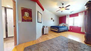 Bedroom with light wood-style floors, ceiling fan, a textured ceiling, and vaulted ceiling