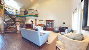 Living room featuring high vaulted ceiling, arched walkways, stairs, and recessed lighting