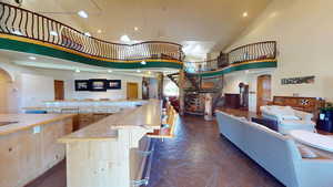 Bar featuring arched walkways, high vaulted ceiling, light countertops, light brown cabinetry, and recessed lighting