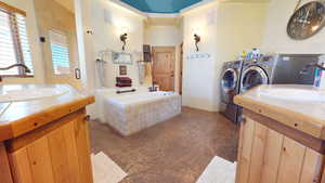 Bathroom with washer and clothes dryer, a bath, and two vanities