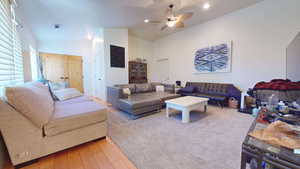 Living area with light wood-style floors, ceiling fan, and high vaulted ceiling