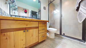 Full bath with vanity, a stall shower, and light tile patterned floors