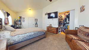 Bedroom featuring vaulted ceiling, carpet, and a walk in closet