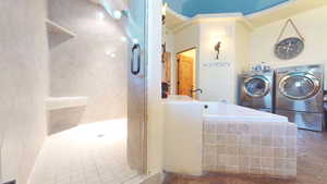 Bathroom featuring a shower stall, a bath, and washer and clothes dryer