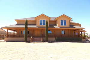 Farmhouse-style home with a porch, stucco siding, and a tile roof