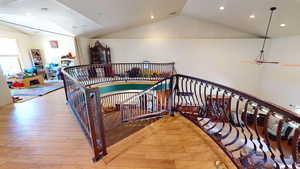 Staircase with recessed lighting, lofted ceiling, and wood finished floors