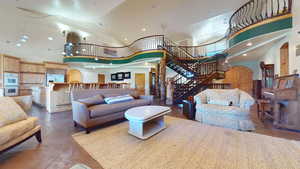 Living room featuring a high ceiling, recessed lighting, arched walkways, and stairway