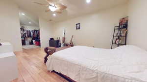 Bedroom featuring light wood-style flooring, recessed lighting, a walk in closet, ceiling fan, and lofted ceiling